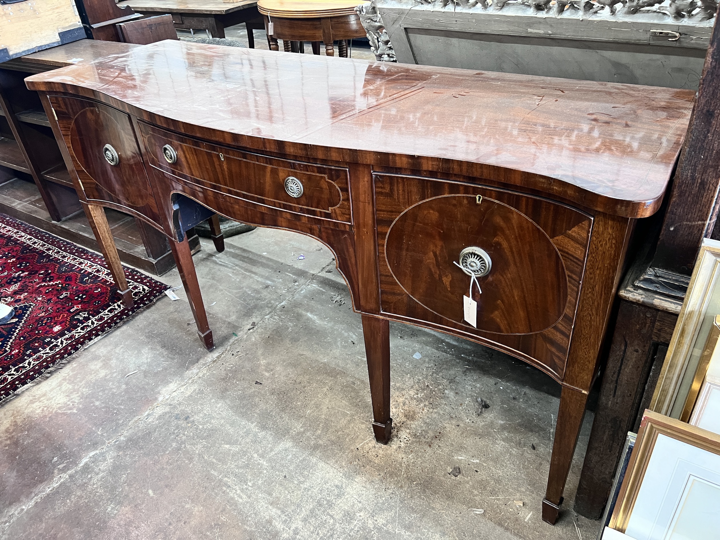 A George III style mahogany serpentine sideboard on square tapered legs, width 184cm, depth 63cm, height 93cm